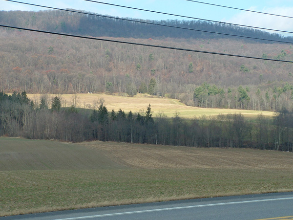 View of fields and woods with a wooded ridge in the background.
