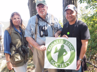 three people posing outdoors with a sign for the Rosalie Edge Society